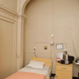 A simple hospital room with a single bed and medical equipment.