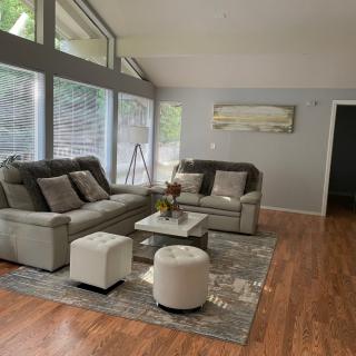 A modern living room with comfortable seating, featuring large windows and neutral decor.