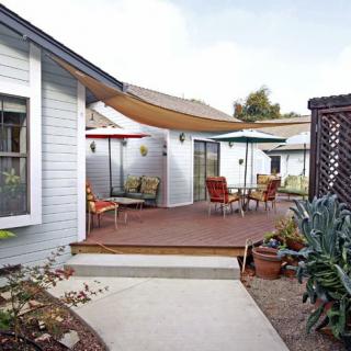 A cozy patio area with seating and sun shades in a backyard setting.