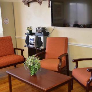 A cozy living room with comfortable chairs, a wooden table, a television, and a stereo system.