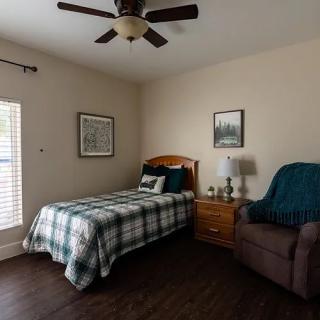 A cozy bedroom with a single bed, nightstand, and chair.