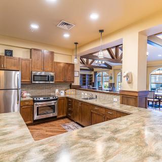 A modern kitchen with wood cabinets, stainless steel appliances, and granite countertops in an open concept layout.