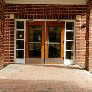A symmetrical entrance with double doors and brick walls.