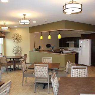 A modern dining room with a kitchen area and stylish lighting.