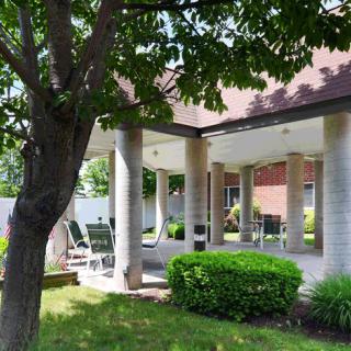 A shaded patio area with seating and garden greenery.