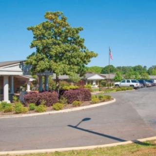 A building surrounded by landscaping with a parking area and clear blue sky.