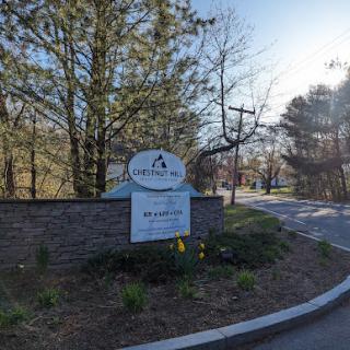 Entrance sign surrounded by trees, leading to a residential area.