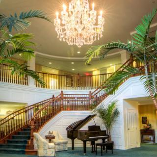 A luxurious interior featuring a grand staircase, elegant chandelier, and a piano.