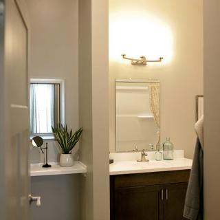 A modern bathroom featuring a mirror, sink, and decorative plant under soft lighting.