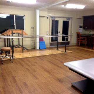 A rehabilitation room equipped with parallel bars and exercise equipment for physical therapy.
