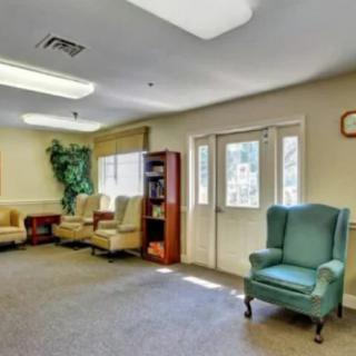A warmly lit waiting room with several armchairs and a bookshelf against the wall.