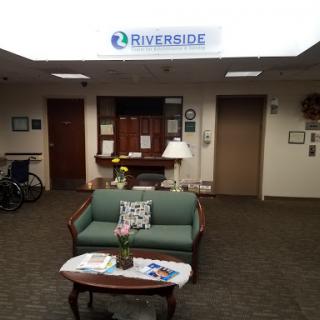 A welcoming lobby area featuring a green couch and reception desk at Riverside.