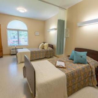 A well-lit hospital room featuring two twin beds, designed for comfort and recovery.