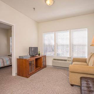 A cozy living room with a sofa, television, and large windows allowing natural light.