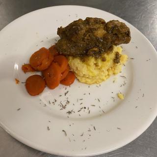 A plated dish featuring crispy chicken, mashed potatoes, and sliced carrots.
