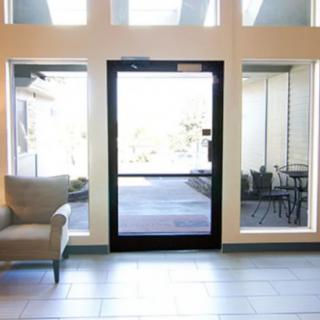 A bright lobby area with a glass door and large windows, featuring a cozy armchair.