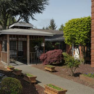 A well-maintained garden with a gazebo and a paved pathway surrounded by lush greenery.