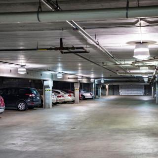 An indoor parking garage with several parked cars and empty spaces.