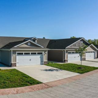 A row of suburban houses with driveways and garages on a clear day.