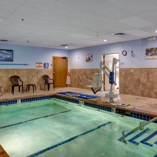 An indoor swimming pool area with chairs and a lift for accessibility.