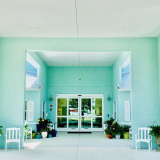 A symmetrical building entrance with plants and chairs.