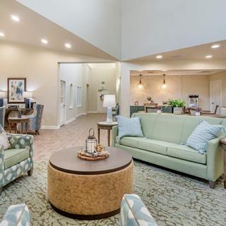 A cozy and well-lit living room with green sofas and a round coffee table.
