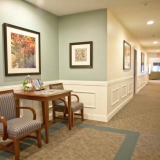 A well-decorated hallway with framed artwork, two chairs, and a table.