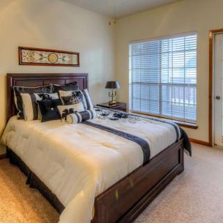 A cozy bedroom with a wooden bed frame, neatly arranged pillows, and a large window allowing natural light to fill the room.