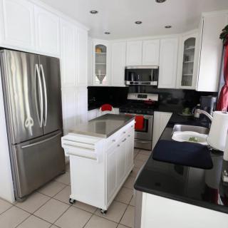 A modern kitchen featuring white cabinets, black countertops, and stainless steel appliances.