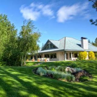A beautiful residential house surrounded by lush greenery under a clear blue sky.