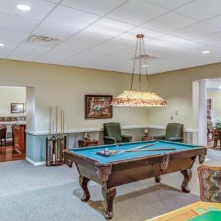 A well-lit billiards room with a pool table and comfortable seating.