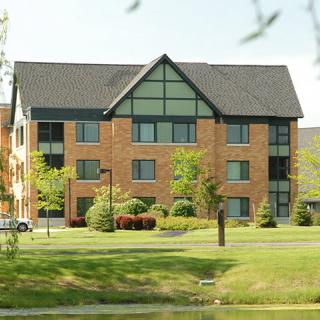 A brick residential building surrounded by trees and greenery.