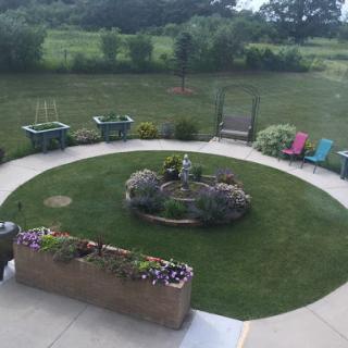 A serene garden view featuring a circular floral arrangement and colorful seating areas.