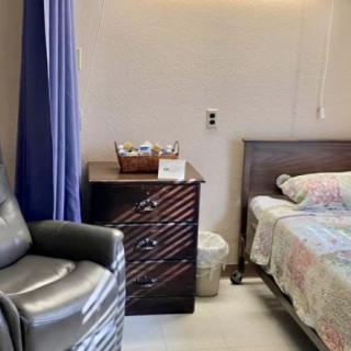 A cozy bedroom with a bed, armchair, and nightstand.