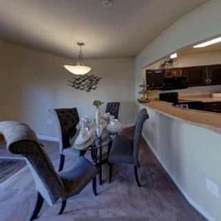 A modern dining area with a set table and view of the kitchen.