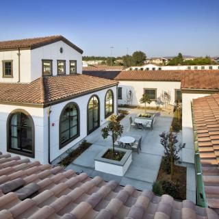 A beautiful Spanish-style home featuring a central courtyard with terracotta roof tiles and arched windows.
