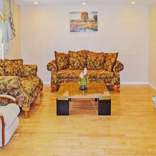 A cozy living room with patterned sofas, a glass coffee table, and wooden flooring.