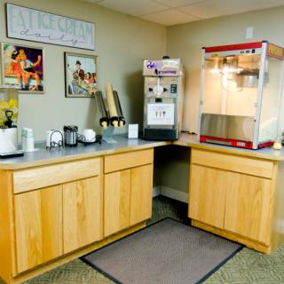 A cozy concession stand setup featuring a popcorn machine and a beverage station with posters on the wall.