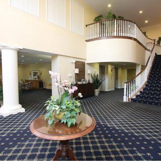 A spacious hotel lobby with a grand staircase and decorative plants.