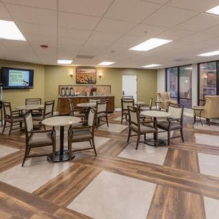A modern dining area with tables and chairs, illuminated by overhead lighting.
