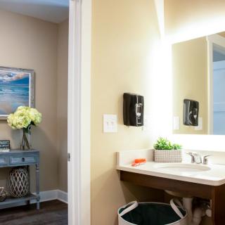 A well-lit bathroom featuring a modern sink, decorative flowers, and wall art.