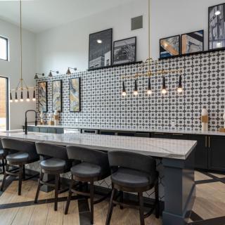 A modern kitchen with a stylish island, bar stools, and decorative tile backsplash.