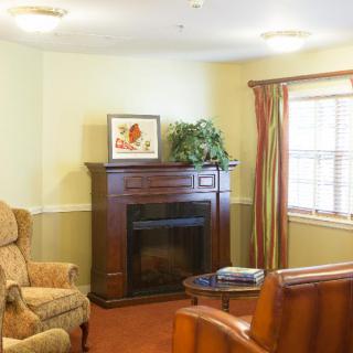 A cozy living room with a fireplace, armchair, and window with curtains.