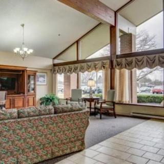 A spacious living room with a large sofa, chandelier, and expansive windows allowing natural light.