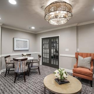 A cozy living room with elegant dcor, featuring a round coffee table, an armchair, and a dining set under a stylish chandelier.