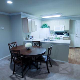 A cozy kitchen and dining area with a round table and chairs, featuring bright lighting and modern decor.