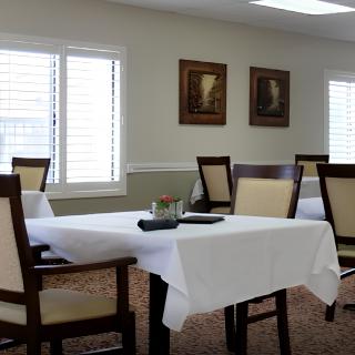 A dining room with a table and chairs, featuring framed art on the walls.