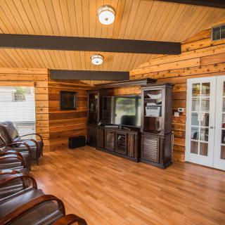 A cozy living room with wood paneling, leather chairs, and an entertainment center.