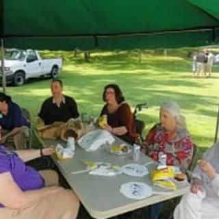 A group of people enjoying a picnic under a tent on a sunny day.