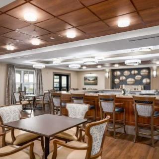 A modern restaurant interior with a bar and seating area featuring wooden furniture and stylish lighting.